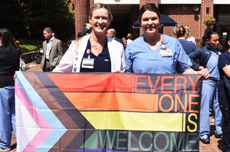 Lindsey Coates and Lauren Coates holding a Pride flag that says Everyone is welcome here